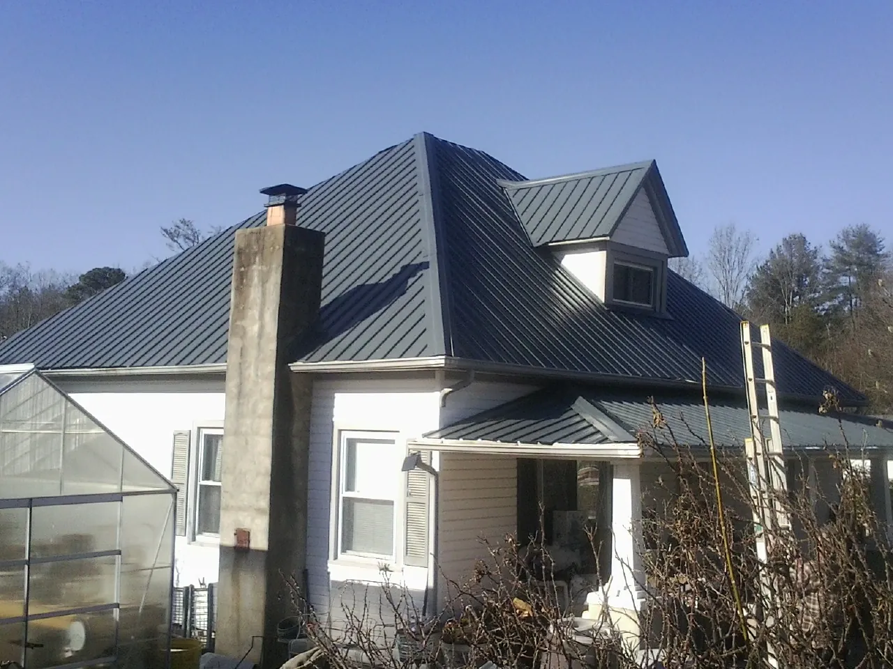 Dark blue standing seam metal roof on a white farmhouse with dormer — Slate & Tile Roof Repair by Roofing Brothers in Oakland City