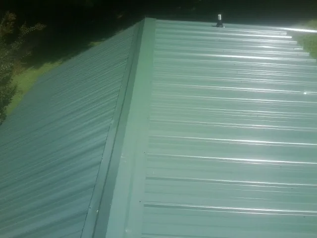 New green metal panels meeting at the ridge of a roof — Flat Roof Repair work by our crew in Oakland City