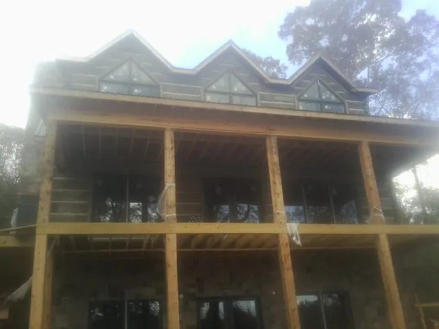 Dormers and porch framing on a large log home under construction — Roof Coating work by our crew in Oakland City