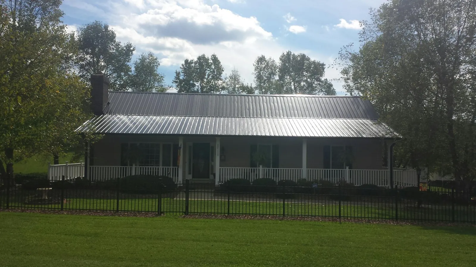 Gray metal roof on a brick ranch with a full width front porch — Gutter Guard Installation work by our crew in Oakland City