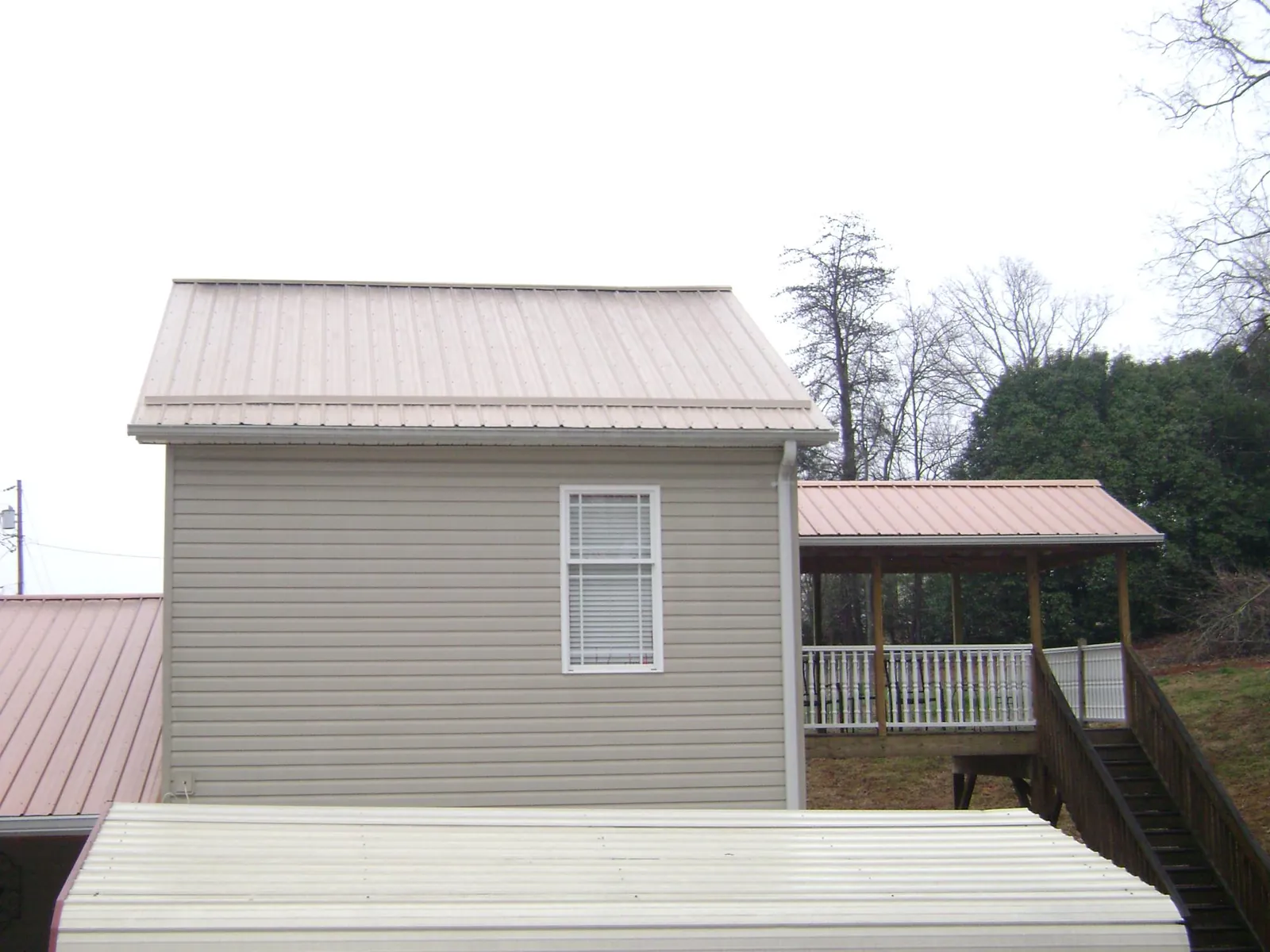 Tan metal roofs on a two story addition and attached porch, from a Roof Replacement job in Oakland City