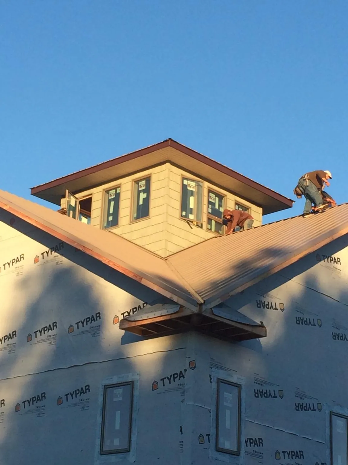 Roofers working around a rooftop cupola on a new metal roof at sunset — Roof Waterproofing in Oakland City by Roofing Brothers